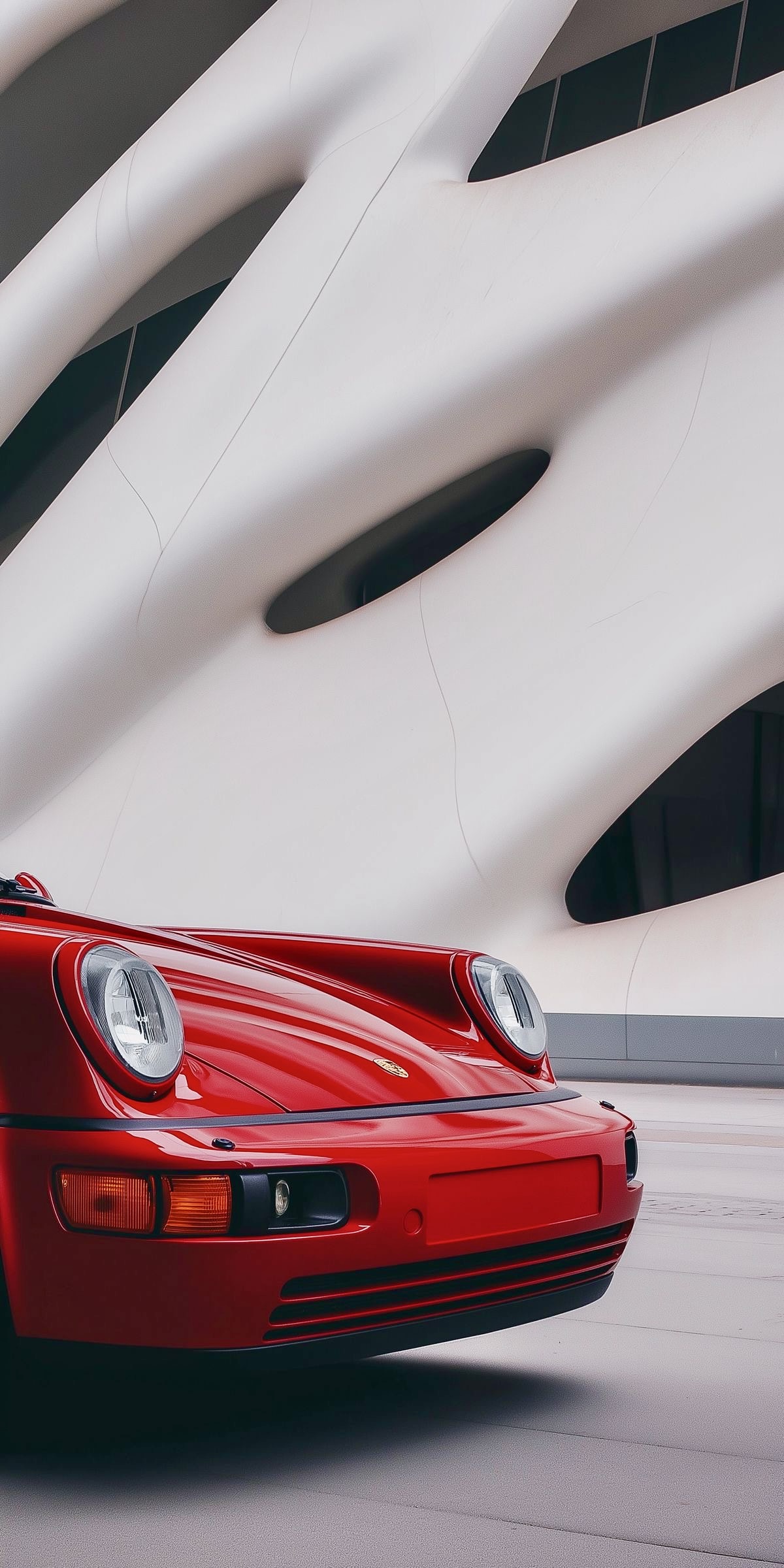 Le linee di una Porsche rossa accostate alle forme di un’architettura contemporanea